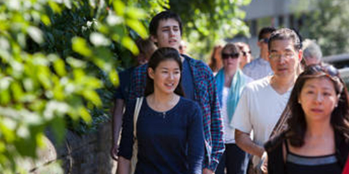 A group of students walking along a sunny street while visiting the University.